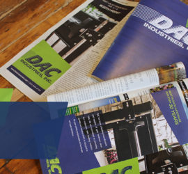 Multiple DAC Industry pamphlets and publications are spread out on a wooden desk.
